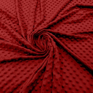 May include: Close-up of a deep red fabric with a textured, dotted pattern. The soft, plush fabric is arranged in a swirl, highlighting the texture and colour. The material appears to be a blanket or throw.