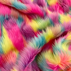 May include: A colorful faux fur fabric with a rainbow ombre pattern. The fabric is soft and fluffy, with a variety of colors including pink, yellow, blue, and purple.