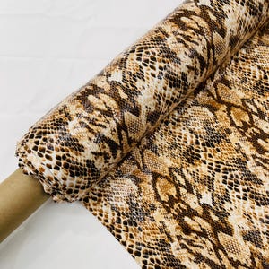 May include: A roll of brown and beige fabric with a snakeskin pattern.