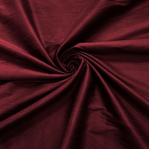 May include: A close-up shot of a deep burgundy fabric with a swirling pattern. The fabric has a subtle sheen, and the folds create shadows and highlights. The texture appears smooth, with a slight variation in color across the surface.