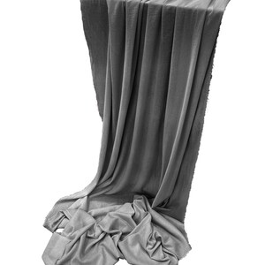 May include: A gray fabric backdrop draped over a surface, with the fabric cascading down in folds and wrinkles.