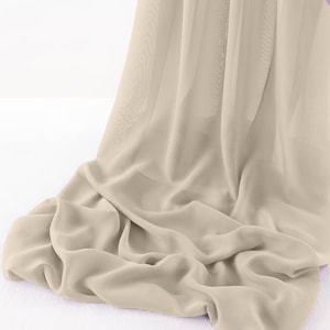 Peut inclure: Un tissu beige fluide, avec des plis souples et un aspect translucide. Le matériau se drape avec grâce, créant une sensation de mouvement et de texture. Le tissu semble léger, peut-être de la mousseline ou un matériau similaire transparent.