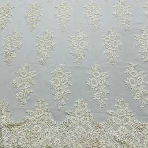 May include: Ivory lace fabric with a delicate floral pattern and scalloped edge.