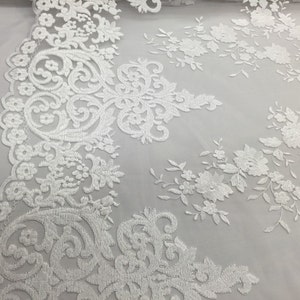 Tecido de renda com elasticidade bidirecional e bordado de flores brancas. Ideal para casamentos, noivas, bailes de formatura e camisolas. Vendido por metro.