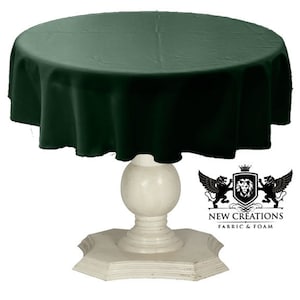 May include: A dark green round tablecloth draped over a white pedestal table. The tablecloth is made of a smooth, soft fabric. The table has a round top and a pedestal base with a decorative design.