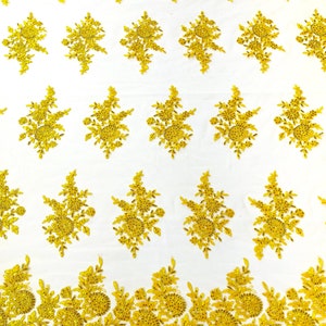 Puede incluir: Tela de encaje floral dorada con un patrón delicado. El encaje tiene un borde festoneado y es perfecto para agregar un toque de elegancia a cualquier proyecto.