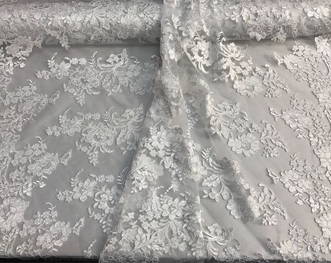 White floral design embroider and corded on a mesh lace fabric--sold by the yard.