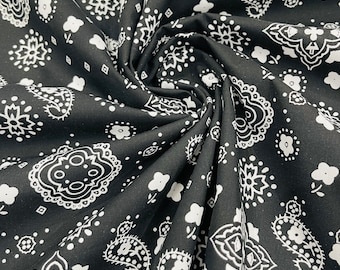Könnte beinhalten: Schwarzer Stoff mit einem weißen Paisley-Muster. Der Stoff ist gefaltet und zeigt das sich wiederholende Muster.