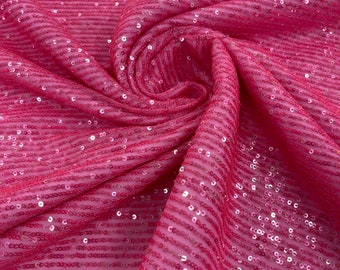 May include: Pink fabric with a striped pattern and sequins. The fabric is folded and draped.