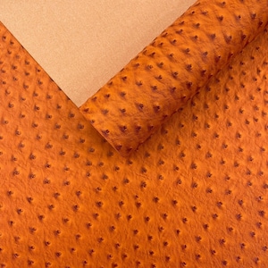 Vinilo para tapicería con textura de piel sintética color avestruz naranja, 54" de ancho.