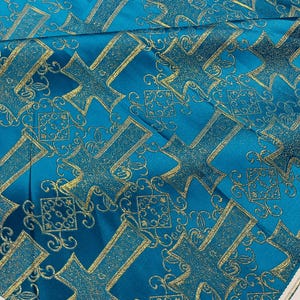 May include: Teal fabric with a gold cross pattern. The fabric has a subtle sheen and a textured surface.