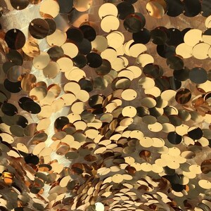 May include: Gold sequin fabric with a mesh backing. The sequins are round and have a slight shimmer.