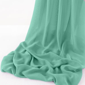 May include: A soft, flowing piece of mint green fabric draped over a white surface. The fabric is sheer and has a delicate texture.