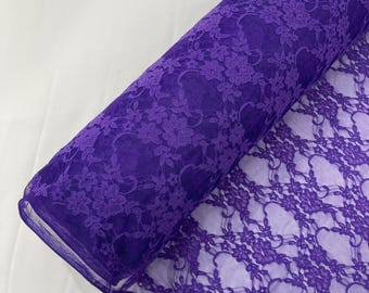 Puede incluir: Un rollo de tela de encaje de color morado vibrante con un delicado patrón floral. El material es semitransparente con una base de malla fina, mostrando intrincados detalles de bordado a lo largo de la longitud del rollo de tela desplegado.