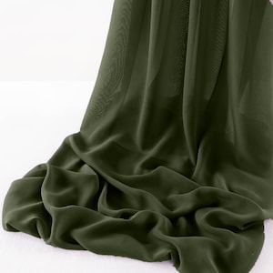Peut inclure: Un morceau de tissu vert doux et fluide drapé sur une surface blanche. Le tissu a une qualité transparente et est plié de manière à montrer sa texture.