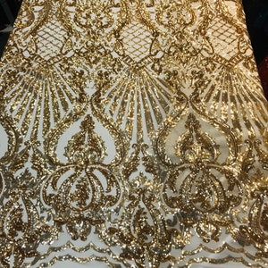 May include: Gold sequin fabric with a white mesh backing. The sequins are arranged in a damask pattern.