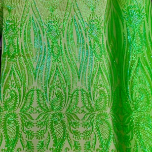 May include: Green sequin fabric with a paisley pattern. The sequins are iridescent and have a light green color.