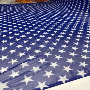 May include: Blue sheer fabric with a white star pattern. The fabric is folded in half, showing the pattern on both sides.