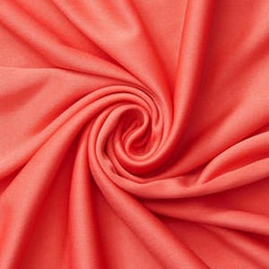 Könnte beinhalten: Ein leuchtend korallenfarbener Stoff mit einer glatten, matten Textur. Das Material ist in einer engen, zentralen Spirale angeordnet, wodurch tiefe, fließende Falten und Schatten entstehen, die über den gesamten Bildausschnitt strahlen.