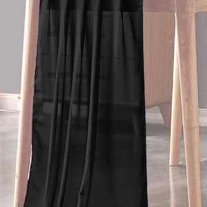 May include: A black sheer table runner draped over a wooden table. The runner is made of a lightweight fabric and has a smooth, flowing texture.