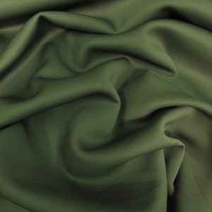 May include: A close-up of a dark green fabric with a smooth, silky texture. The fabric is draped and folded, creating soft, flowing lines.