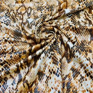 Pu&ograve; includere: Primo piano di un tessuto con un motivo a pelle di serpente marrone e nero.