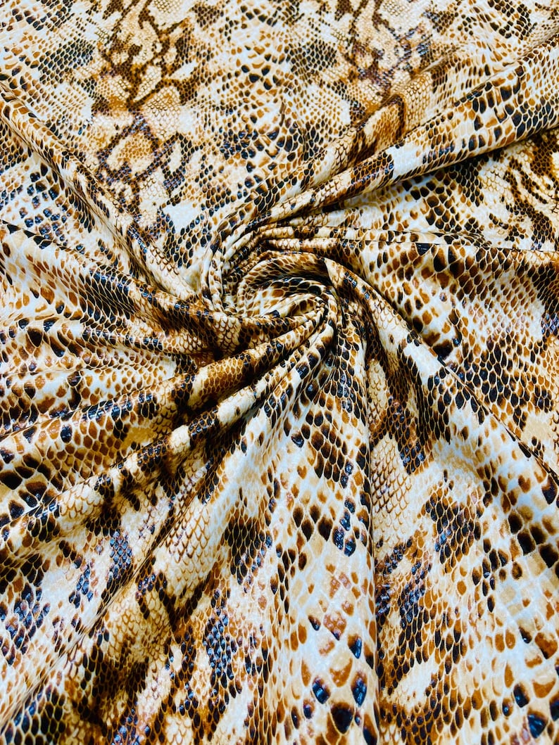 Pu&ograve; includere: Primo piano di un tessuto con un motivo a pelle di serpente marrone e nero.