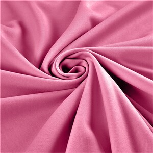 May include: A close-up shot of a swirl of pink fabric. The fabric has a smooth texture and is arranged in a spiral pattern, with the center of the swirl in sharp focus. The color is a vibrant, medium pink.
