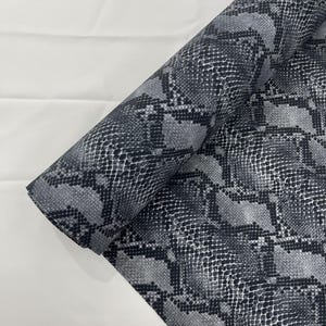 Peut inclure: Un rouleau de tissu à motif serpent noir et blanc.
