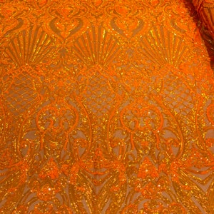 May include: Orange and gold sequined fabric with a damask pattern. The fabric is sheer and has a delicate, intricate design.