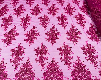 Fuchsia floral design embroidery on a mesh lace with sequins and cord-sold by the yard.