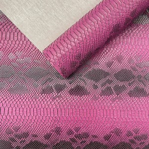 May include: A sheet of magenta and dark grey snakeskin patterned leather with a textured, scale-like surface. The material is rolled at the top, revealing a light beige, fabric-like underside with a fine, woven texture visible in the corner.