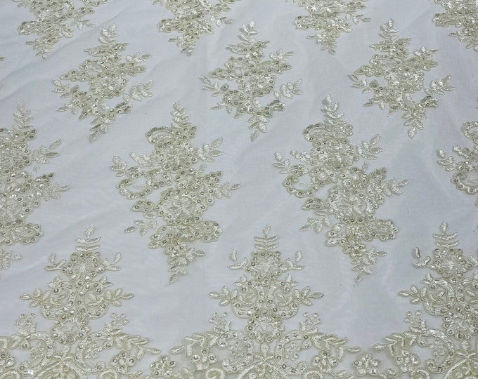 Ivory corded flowers embroider with sequins on a mesh lace fabric-sold by the yard.