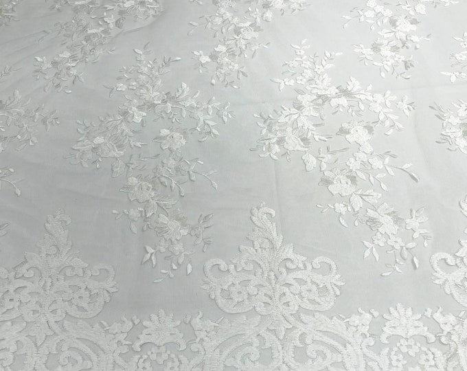 White flowers flat lace embroider on a 2 way stretch mesh sold by the yard.