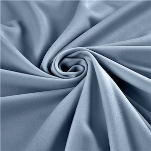 May include: A close-up shot of a light blue fabric, artfully arranged in a spiral. The fabric has a smooth texture with subtle variations in tone, creating depth and visual interest. The folds and curves of the material are highlighted by the lighting.