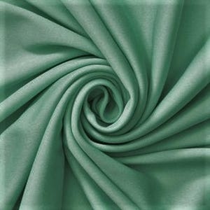 Puede incluir: Una tela de color verde salvia sólido con una textura suave y mate, dispuesta en un patrón de espiral central apretado. El material presenta pliegues profundos y fluidos con sombras suaves que irradian hacia afuera desde el centro.