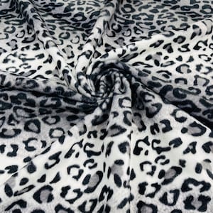May include: White fabric with a black and gray leopard print pattern. The fabric is soft and plush, with a fuzzy texture.
