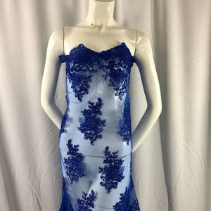 Puede incluir: Tela de encaje floral azul real con un patr&oacute;n delicado. El encaje es transparente y tiene una textura suave y fluida.