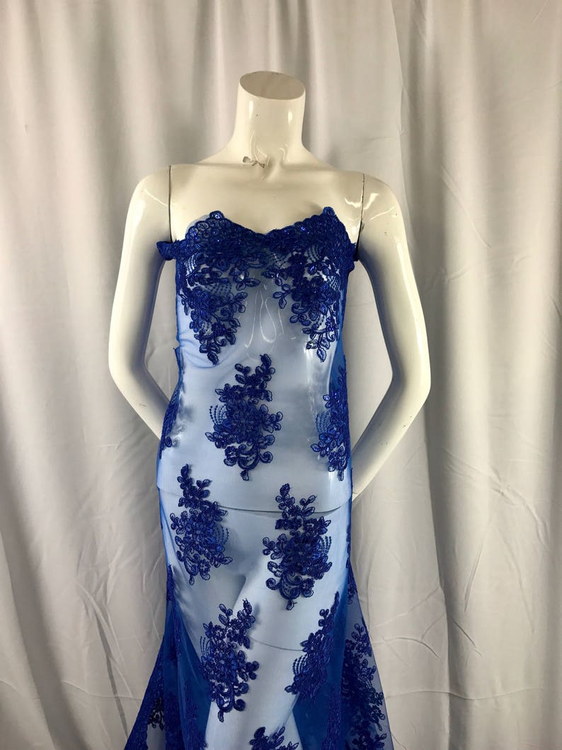 Puede incluir: Tela de encaje floral azul real con un patr&oacute;n delicado. El encaje es transparente y tiene una textura suave y fluida.