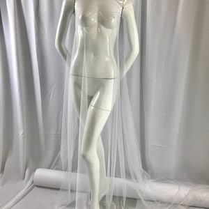 May include: White sheer tulle fabric with a dotted pattern. The fabric is draped over a white dress form.
