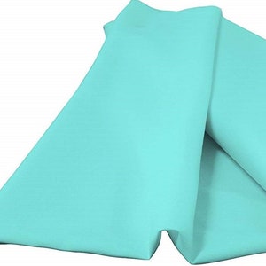 Op de afbeelding: Een stuk licht turquoise stof dat over zichzelf is gevouwen, met een gladde, matte textuur en een consistente kleur. Het materiaal is gedrapeerd om zachte plooien en lagen te tonen, wat zorgt voor een strak en uniform uiterlijk.