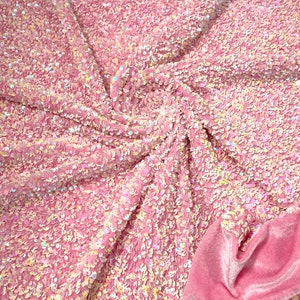 May include: Pink iridescent sequins fabric with a pink velvet backing. The sequins are small and densely packed, creating a shimmering effect.
