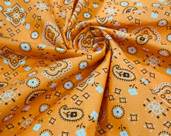 Könnte beinhalten: Orangener Stoff mit einem weißen und schwarzen Paisley-Muster. Der Stoff ist gefaltet und hat eine strukturierte Oberfläche.