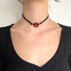 gothic carnelian choker, made with a 20mm red carnelian gemstone donut, with black cord ,worn around the neck of a woman.