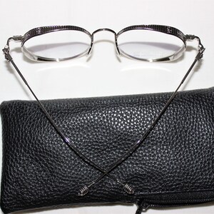 May include: Silver-toned round eyeglasses with a black leather case and a black microfiber cleaning cloth.