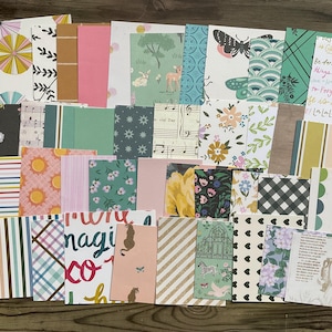 以下が含まれることがあります： 黒い持ち手と「But First, Coffee」の文字が黒い手書き風フォントで書かれた白いセラミックマグ。マグカップは白い表面に置かれています。