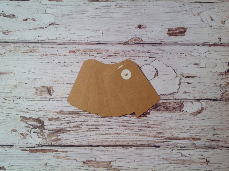 May include: A stack of five brown paper gift tags with a white circle in the center of the top tag.