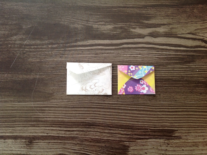 May include: Two small envelopes, one white with a patterned design and one with a colorful floral pattern.