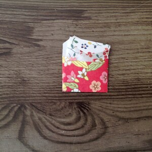 May include: A small red envelope with a floral pattern. The envelope is folded in half and has a white lining.