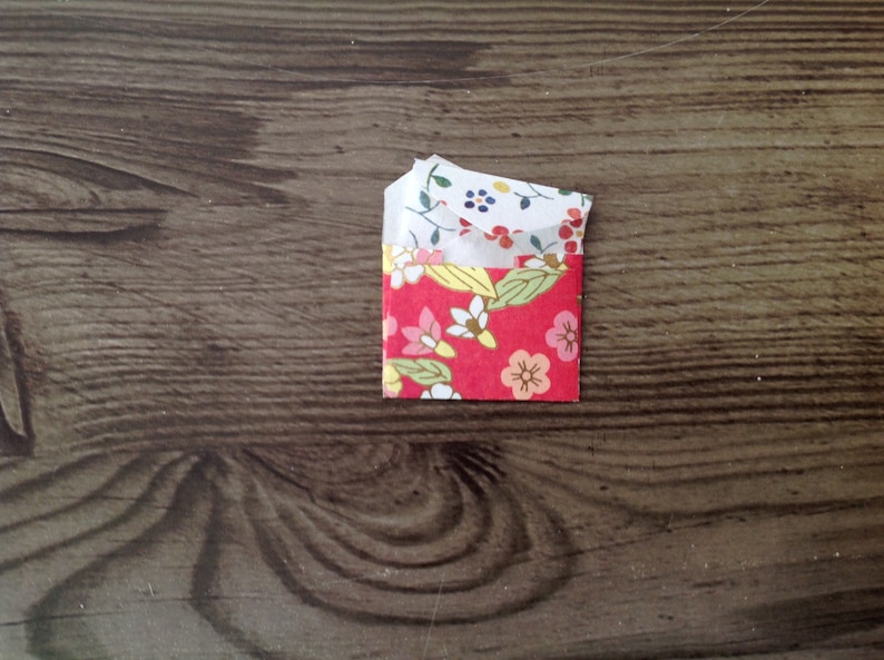 May include: A small red envelope with a floral pattern. The envelope is folded in half and has a white lining.